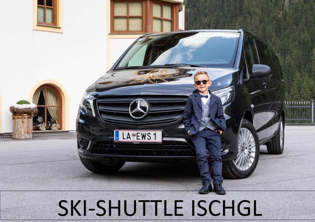 Ein Junge in einem Anzug, der vor einem Auto sitzt. in der Unterkunft Hotel Edelweiß-Schlössl in Kappl