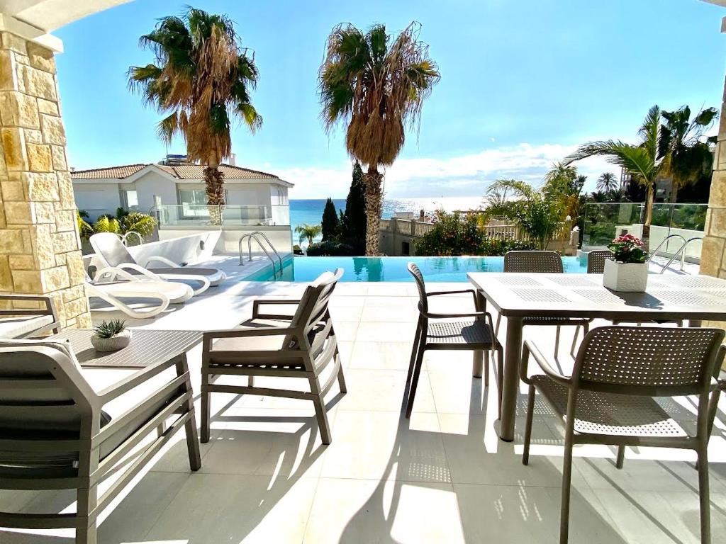a patio with tables and chairs and a pool at coral bay beach villa in Paphos City