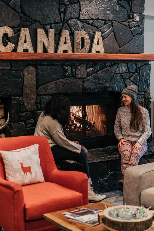 two women sitting in front of a stone fireplace at Basecamp Lodge Canmore in Canmore