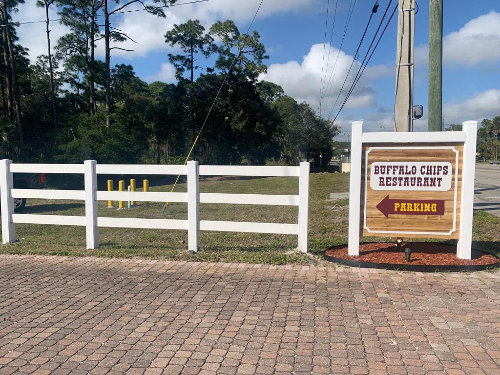 a white fence with a sign in front of it at Buffalo Chip's Ranch House Motel in Bonita Springs