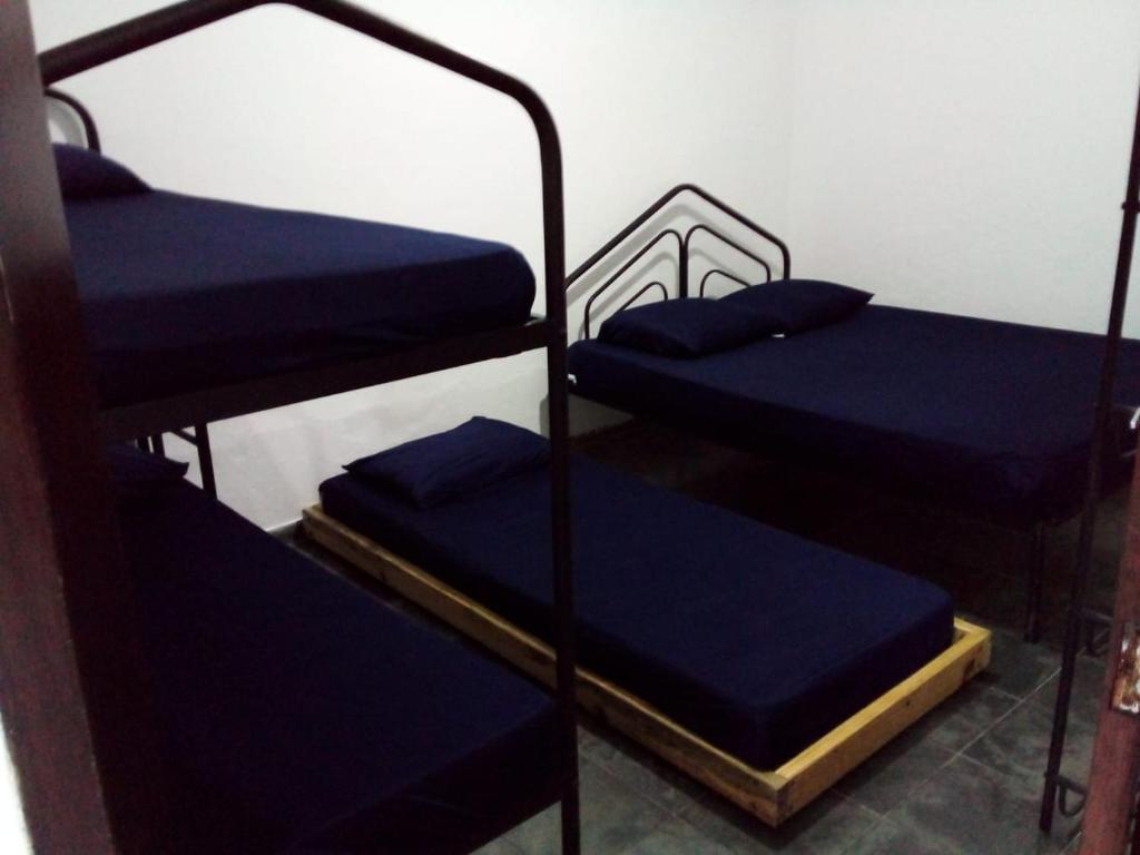 Cette chambre comprend 3 lits superposés avec des draps bleus. dans l'établissement Excellence Apart, à Ubatuba