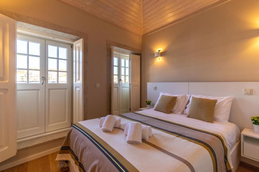 a bedroom with a large bed with towels on it at Portucale Guest House- Self check-in in Porto