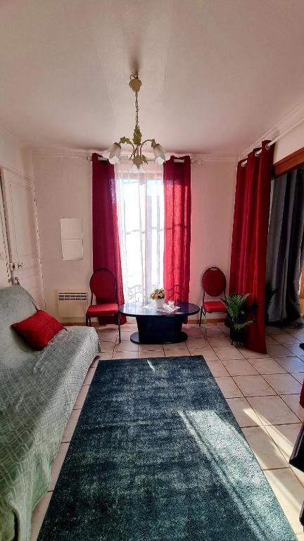 a living room with red curtains and a couch at Sympa Appartement avec 2 chambres séparées in Persan