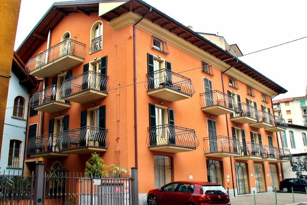 an orange building with balconies and a red car parked in front at Casa Vacanze Touring in Verbania