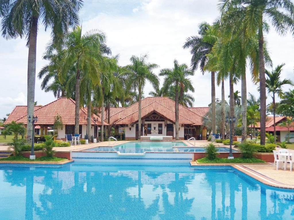 a swimming pool with palm trees in front of a house at Hotel Campestre Los Chiguiros in Villavicencio
