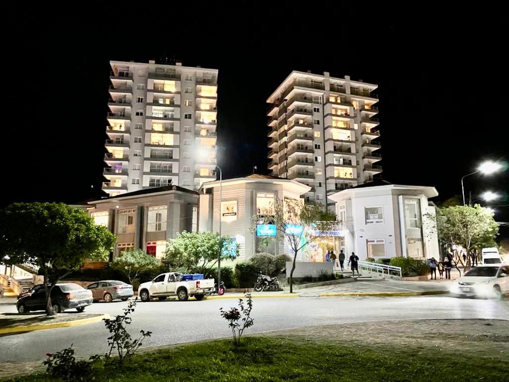 dos edificios altos por la noche con autos estacionados en un estacionamiento en Torre Las Grutas en Las Grutas