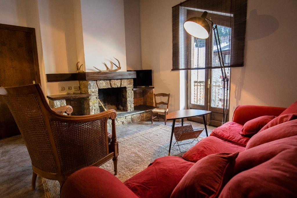 ein Wohnzimmer mit einem roten Sofa und einem Kamin in der Unterkunft JAT MOUNTAIN HOUSES - Casa Jarca 2on pis Àtic, a 1km de Canillo in Prats