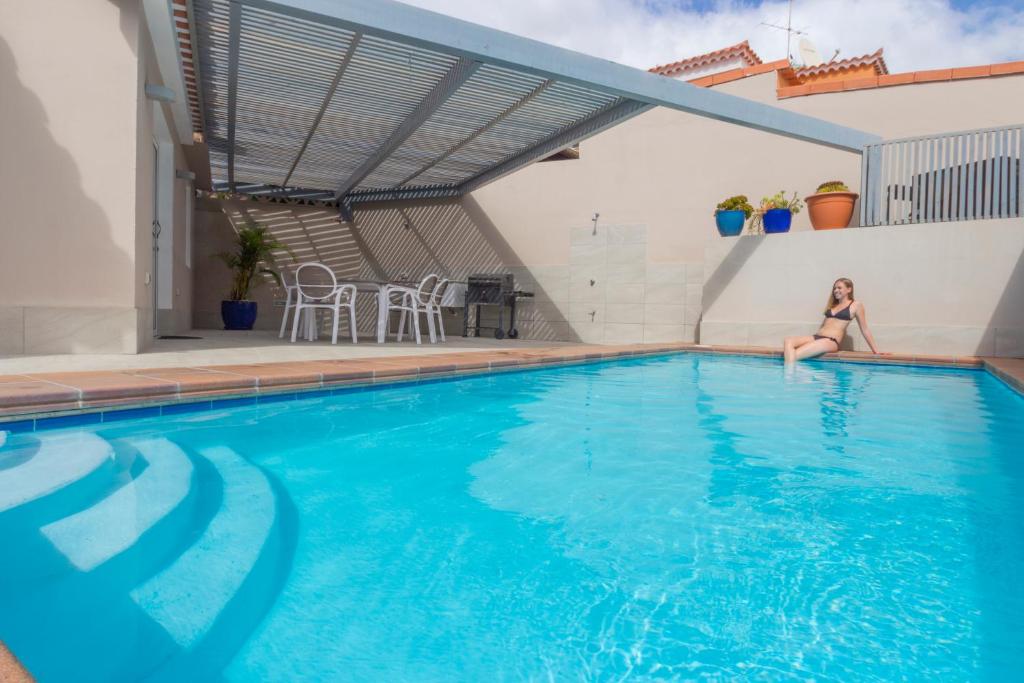 una mujer está sentada en el borde de una piscina en Villa Santiago, en La Playa de Tauro