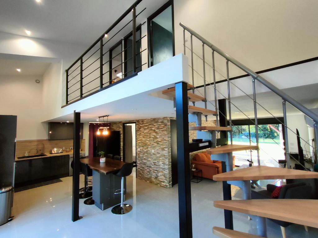 uma casa moderna com uma escada e uma sala de jantar em Maison piscine jeux à la campagne em Camélas