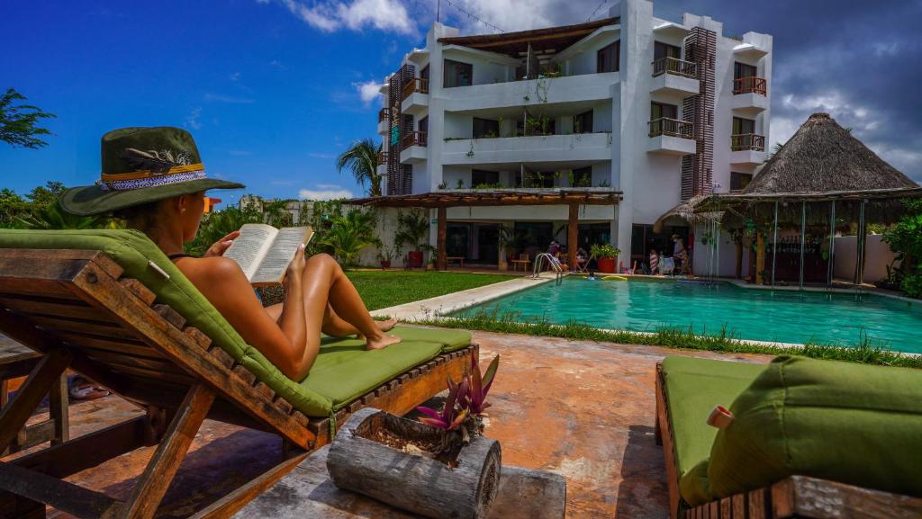 a person sitting in a chair reading a book next to a pool at Hotel Rio Lagartos in Río Lagartos