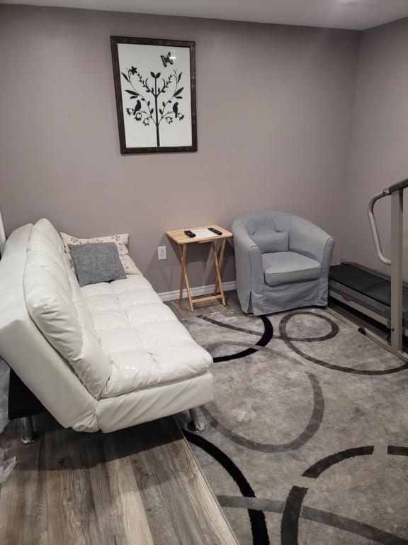 ein Wohnzimmer mit einer weißen Couch und einem Stuhl in der Unterkunft Adorable Studio Basement Suite in South Barrie in Barrie