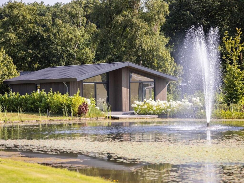 a fountain in a pond in front of a building at Beautiful chalet with a bath, in a holiday park in the Brabant Kempen in Veldhoven