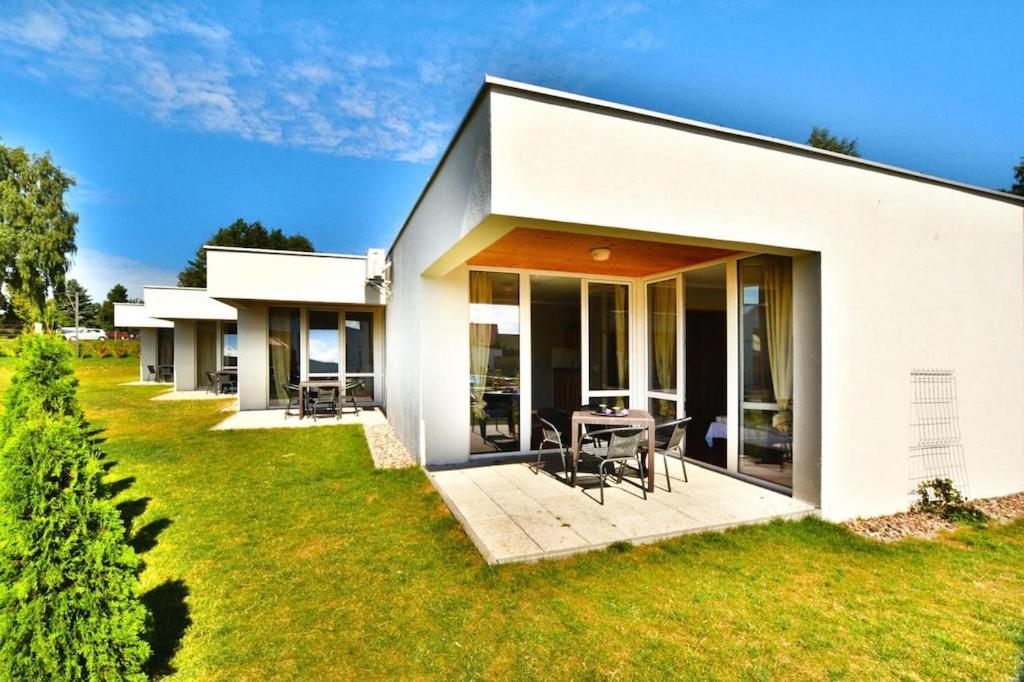 Ein weißes Haus mit einer Terrasse und einem Tisch in der Unterkunft Holiday resort with pool, Sianozety in Sianożęty