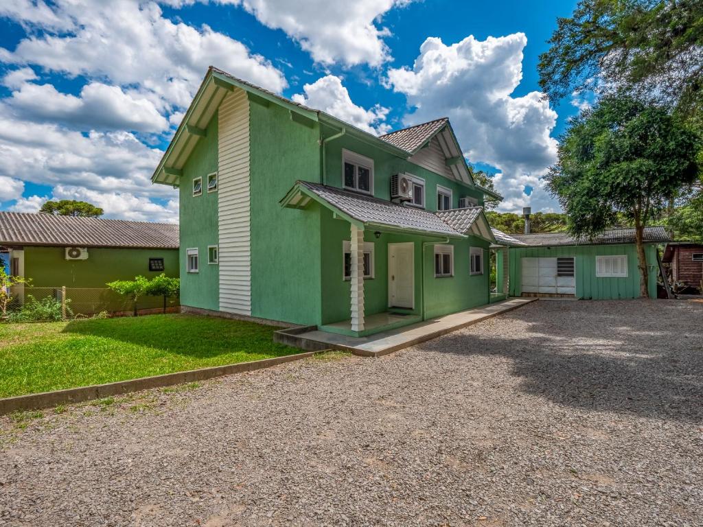 Casa verde y blanca con entrada de grava en Minha Casa em Canela 1, en Canela