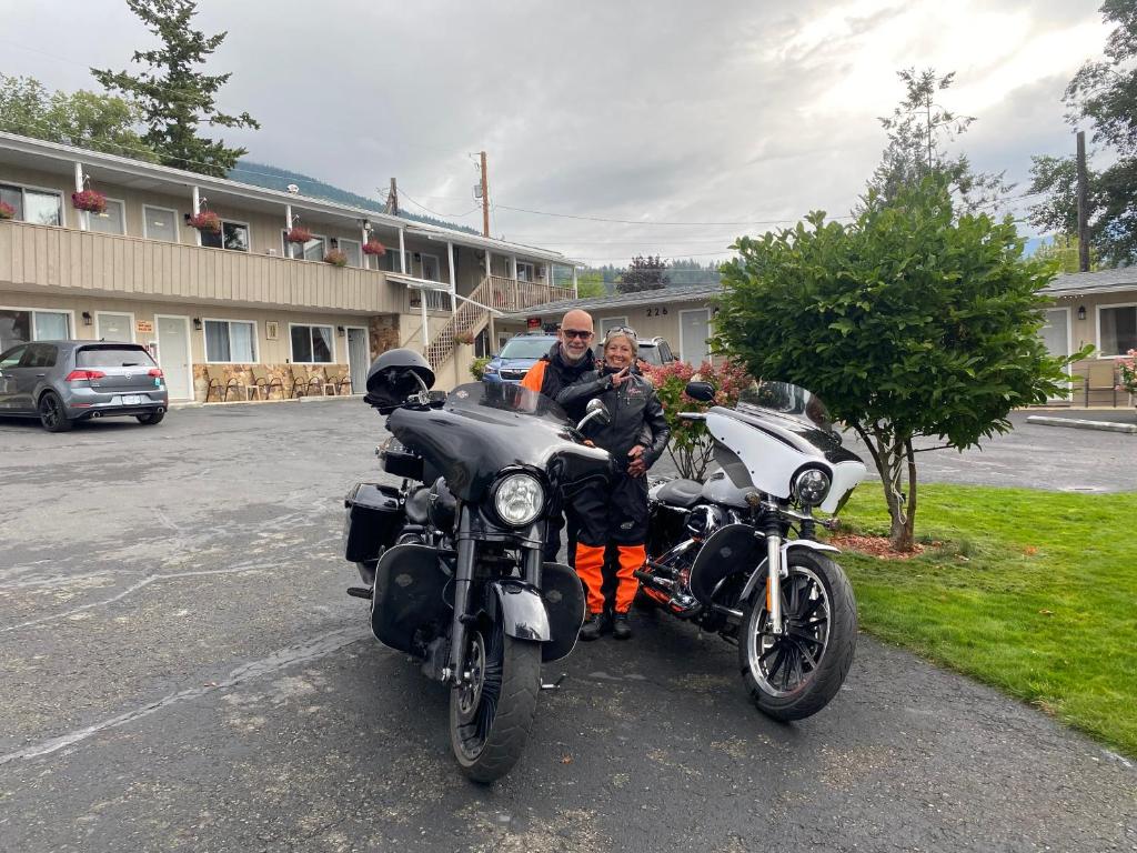 a man standing next to two motorcycles in a parking lot at City Centre Motel in Creston