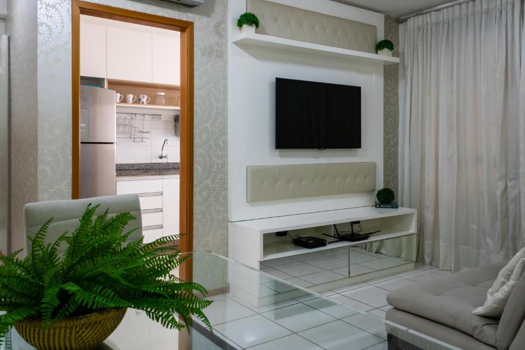 a living room with a television on a wall at Apartamento Família em bairro nobre de Cuiabá! in Cuiabá