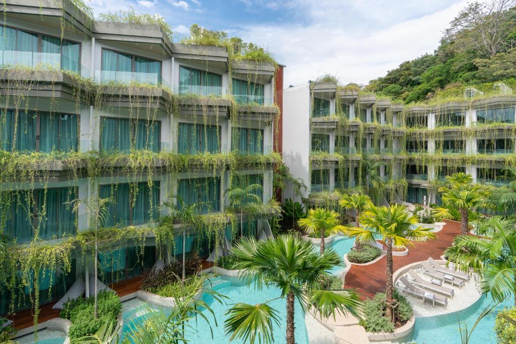 ein Apartmenthaus mit einem Innenhof mit Palmen in der Unterkunft Panwaburi Beachfront Resort - SHA Extra Plus in Panwa Beach