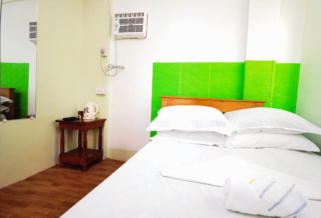 een slaapkamer met een wit bed met een groen hoofdeinde bij RedDoorz D128 Lodge Cagayan Valley in Tuguegarao City