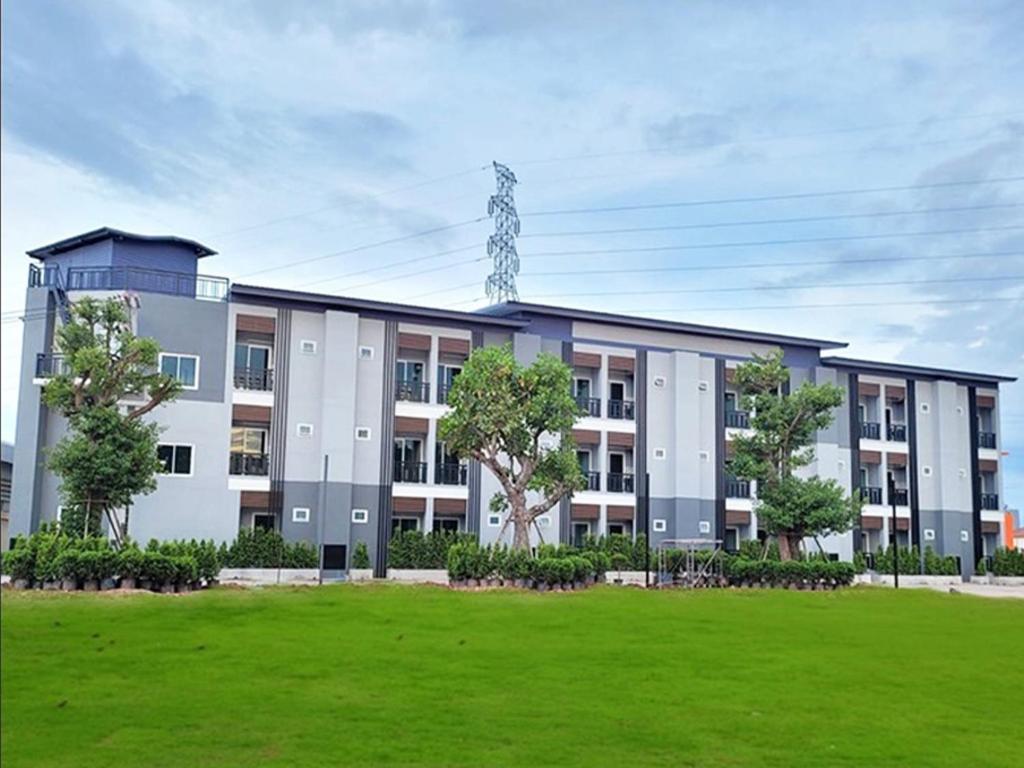 um edifício com um campo verde à sua frente em The S อพาร์ทเม้นท์ em Ban Pra Dok