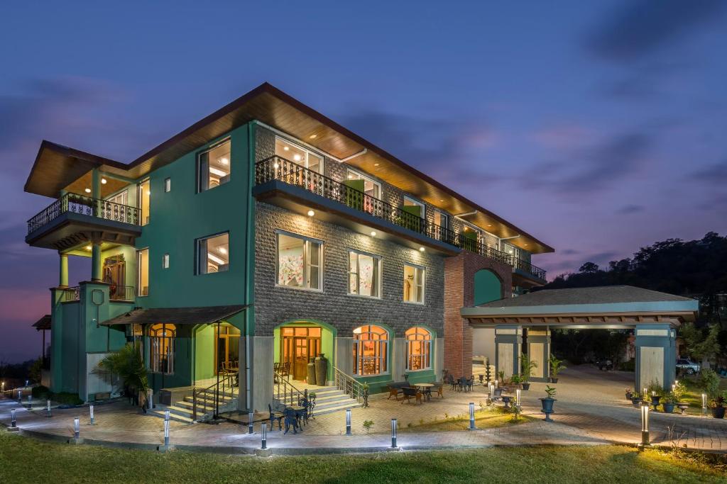 a large green building with a porch at night at The Atman Dharamshala by Leisure Hotels in Dharamshala