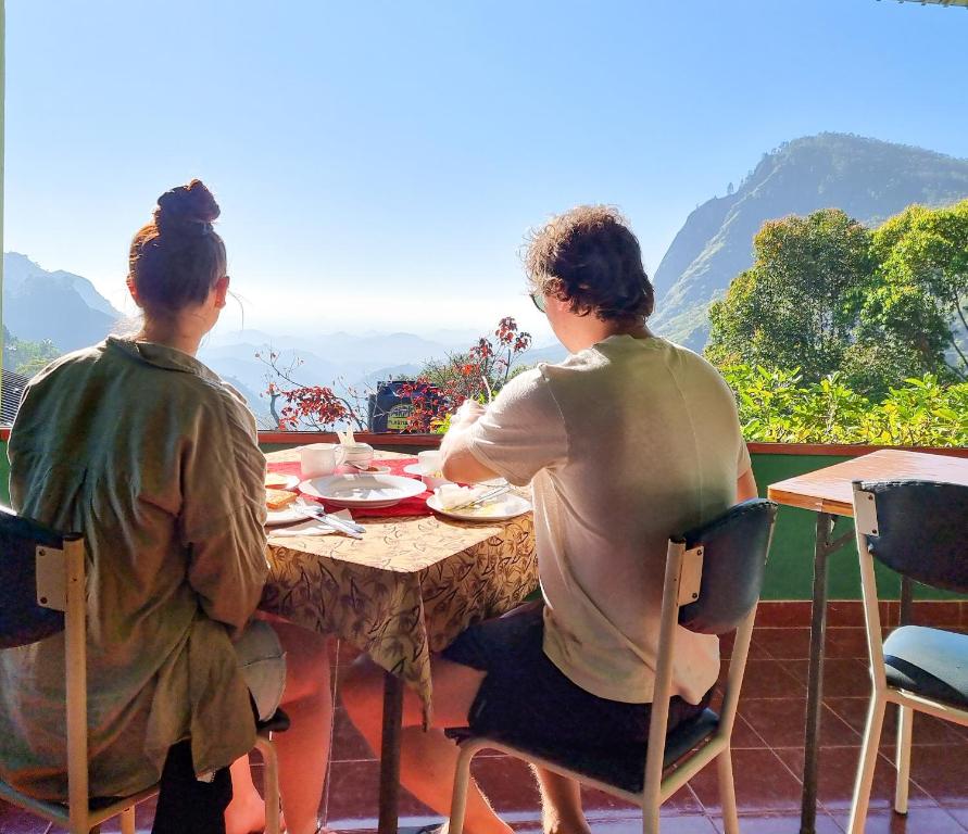two women sitting at a table on a balcony at Hilltop Guest House in Ella
