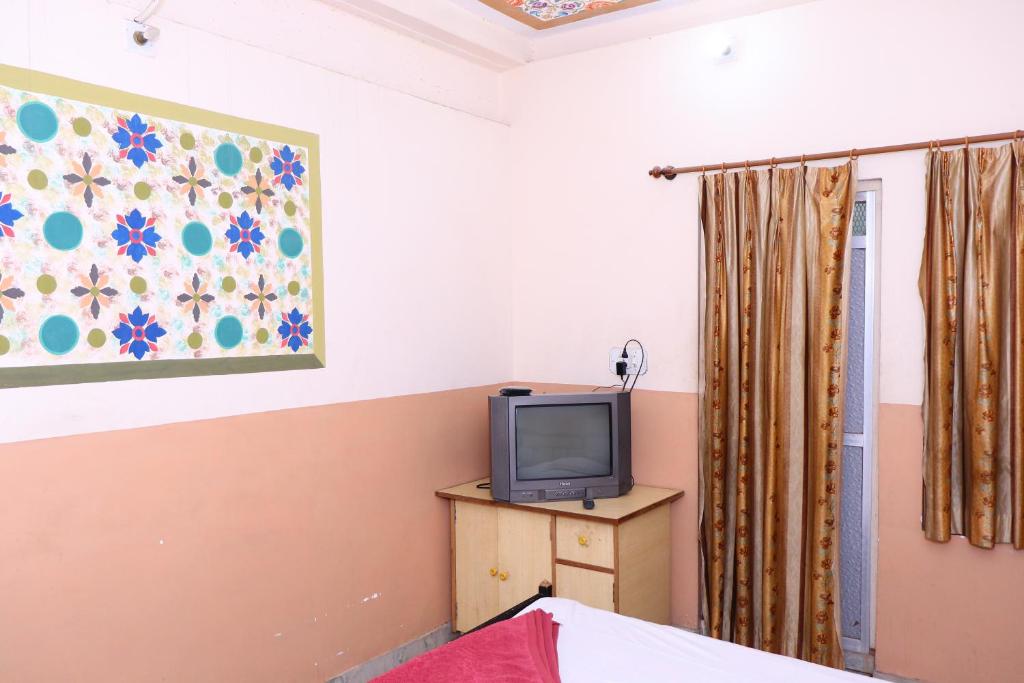 a bedroom with a tv on a dresser with a painting at Jamna vilas Home Stay in Bikaner