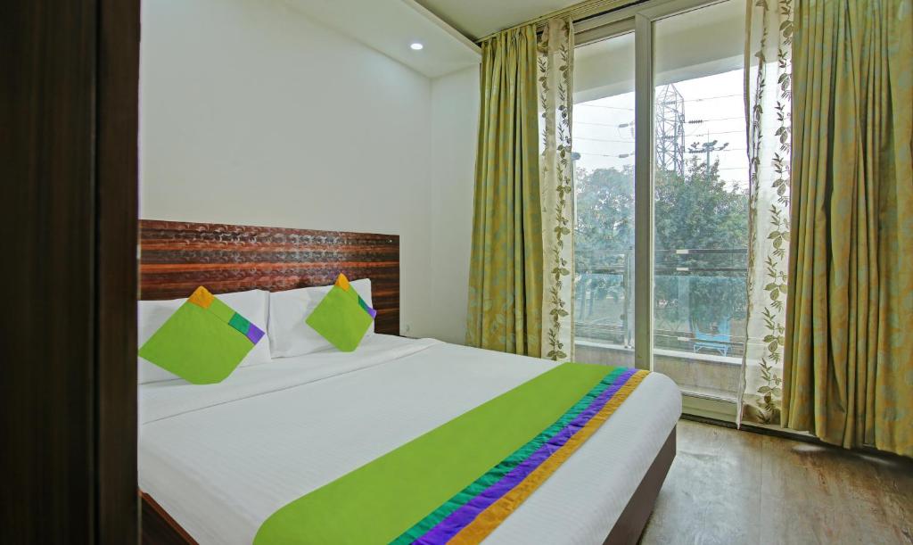 a bedroom with a bed and a large window at Itsy by Treebo - Nyra Sector 22 in Gurgaon
