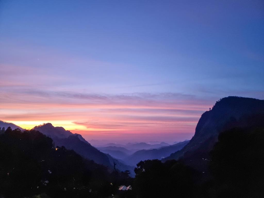 a sunset in the mountains with the sun setting at Hilltop Guest House in Ella