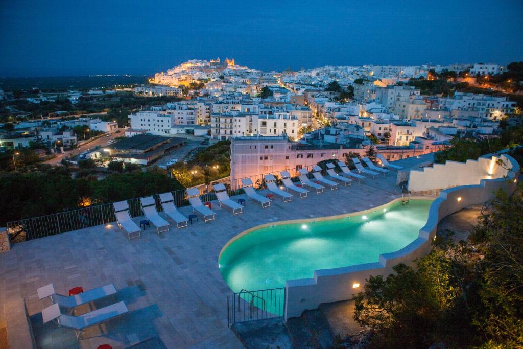 a pool with lounge chairs and a city at night at Monte Sarago Villas in Ostuni