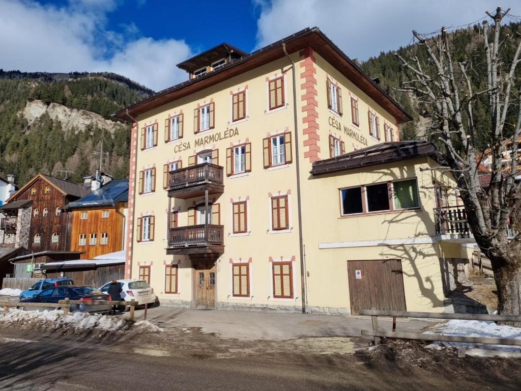 un grande edificio giallo con balcone di CHENINA a Canazei