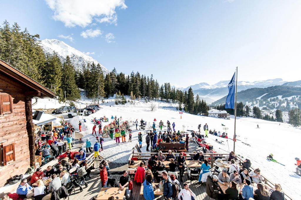 duży tłum ludzi siedzących na stoku narciarskim w obiekcie Berggasthaus Crest'ota w mieście Lenzerheide