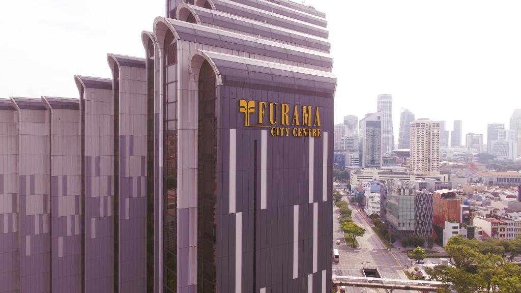 ein hohes Gebäude mit einem Schild an der Seite in der Unterkunft Furama City Centre in Singapur