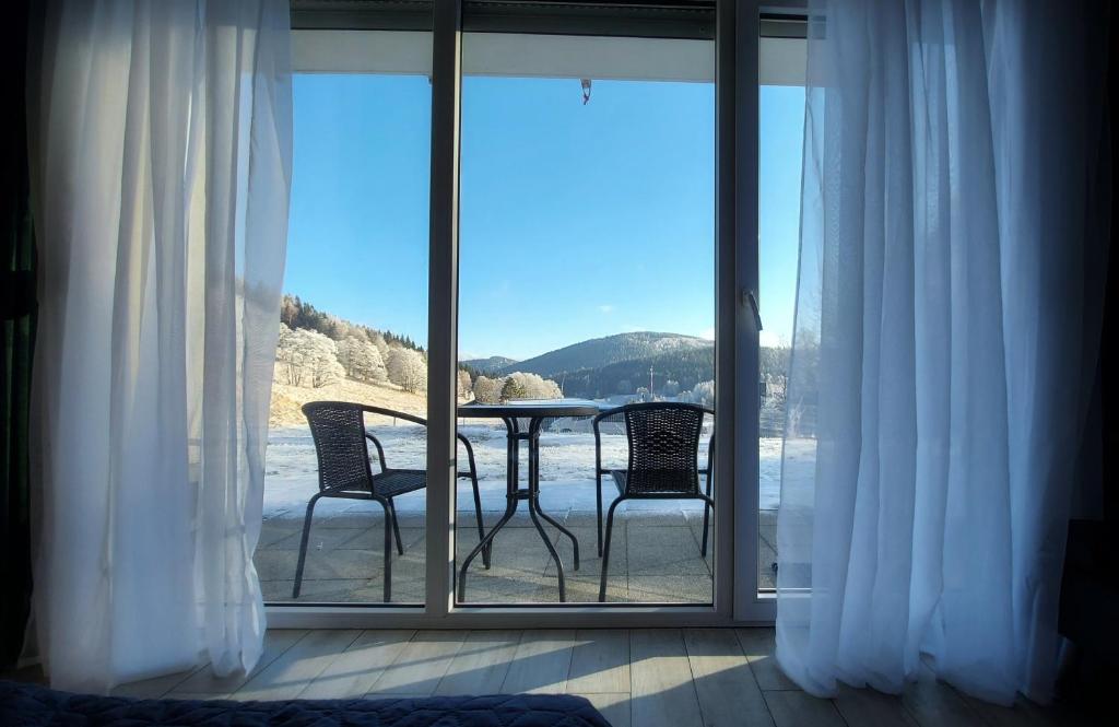 a balcony with a table and chairs and a view of the water at Apartament Pod Wyciągiem - Czarna Góra Resort & SPA in Sienna