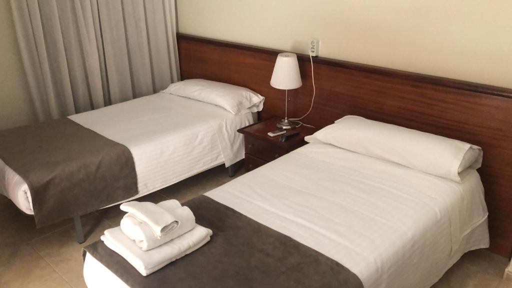 ein Hotelzimmer mit 2 Betten und einer Lampe in der Unterkunft HOTEL EL COMENDADOR in Fuente Obejuna
