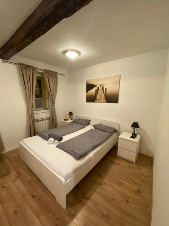 um quarto com uma grande cama branca e pisos em madeira em Rooms and apartments Nokturno em Zagreb