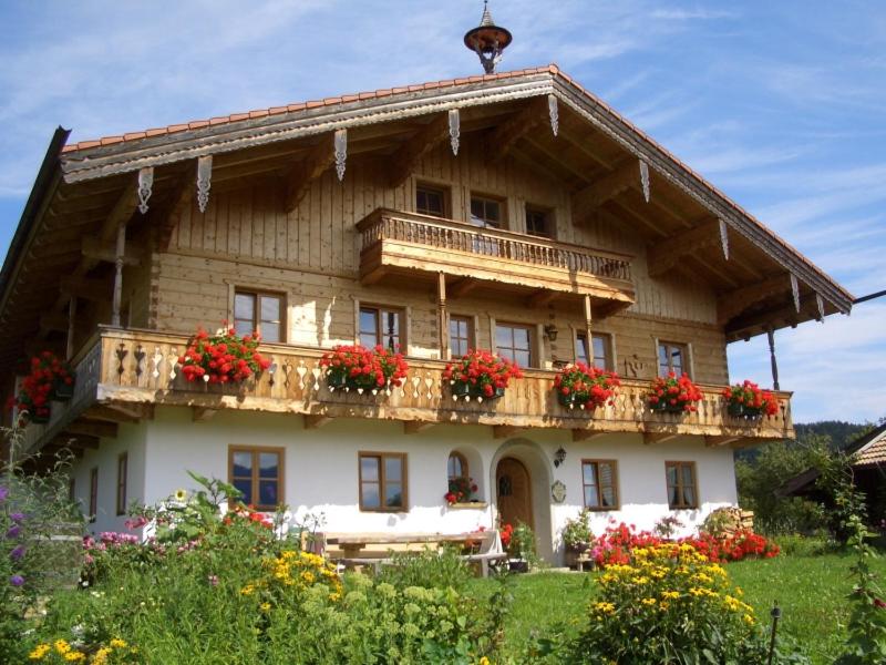 een groot houten huis met bloemen op het balkon bij Huberbauernhof Ferienwohnungen in Piding