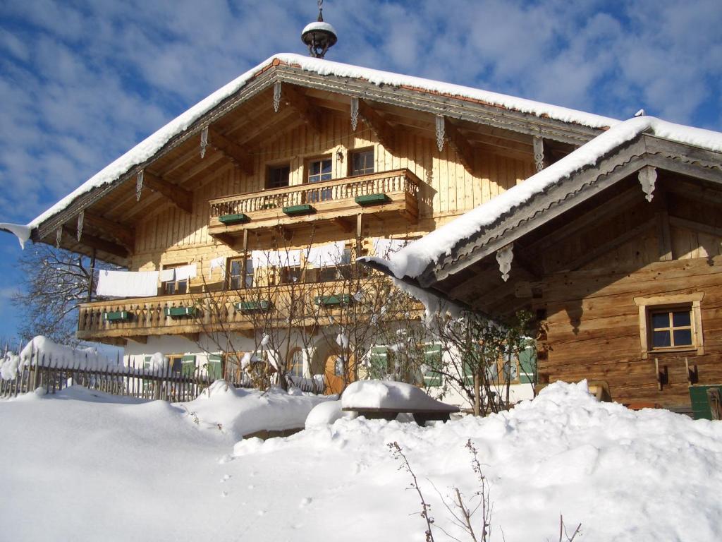 ein Blockhaus mit Schnee auf dem Boden davor in der Unterkunft Huberbauernhof Ferienwohnungen in Piding