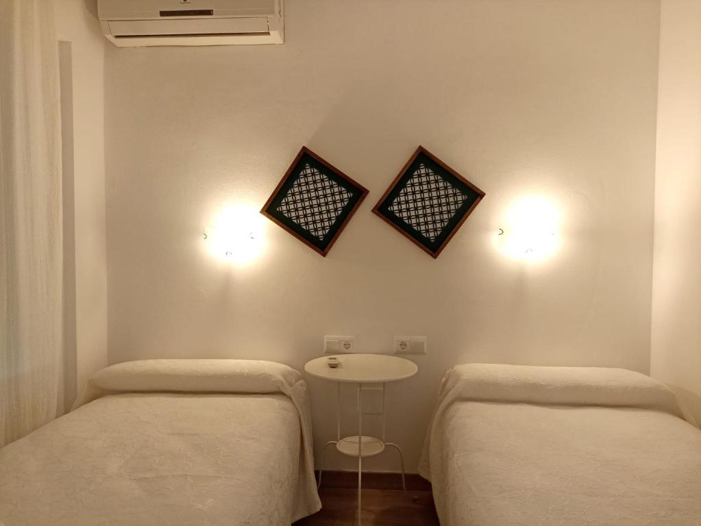 two beds in a room with a table and two lights at El Jardin BeNerja in Nerja