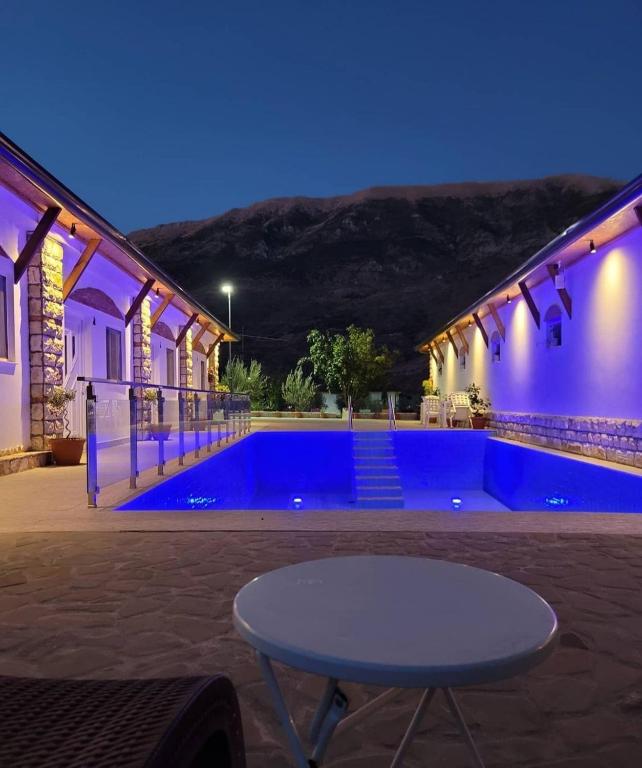 a swimming pool with a table in front of a building at Guesthouse Lord Byron in Tepelenë