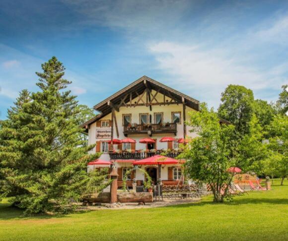 ein großes Gebäude mit roten Sonnenschirmen in einem Park in der Unterkunft Gästehaus Siegllehen in Schönau am Königssee