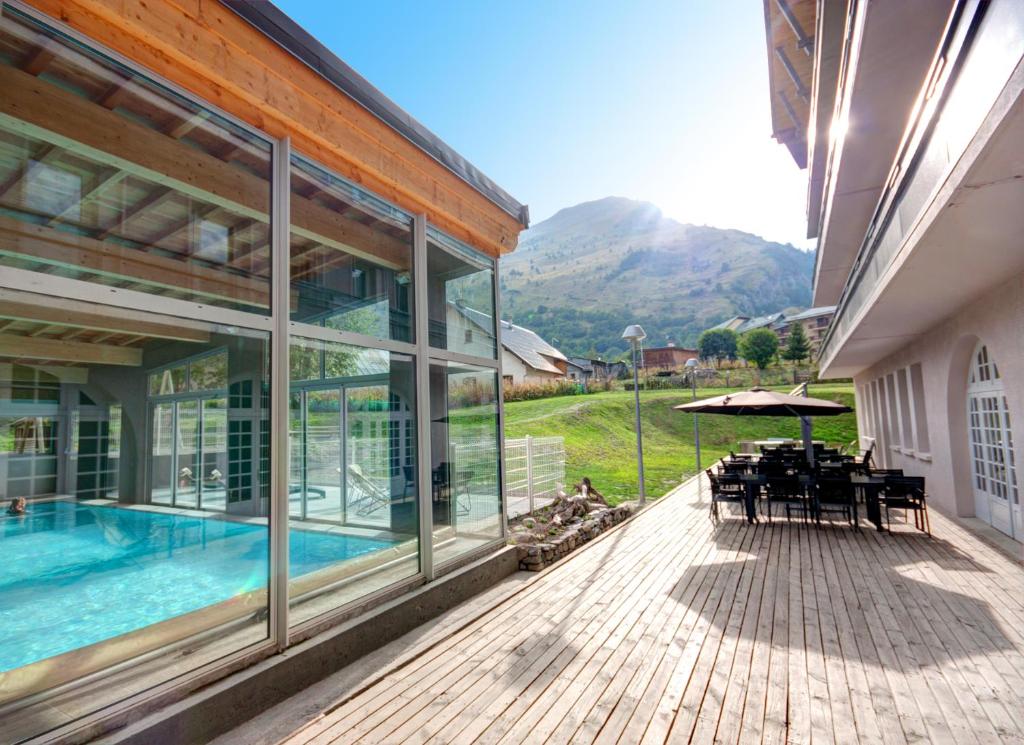 ein Haus mit einem Pool und einer Terrasse mit einem Tisch in der Unterkunft Village Club La Pulka Galibier - Neaclub in Valloire