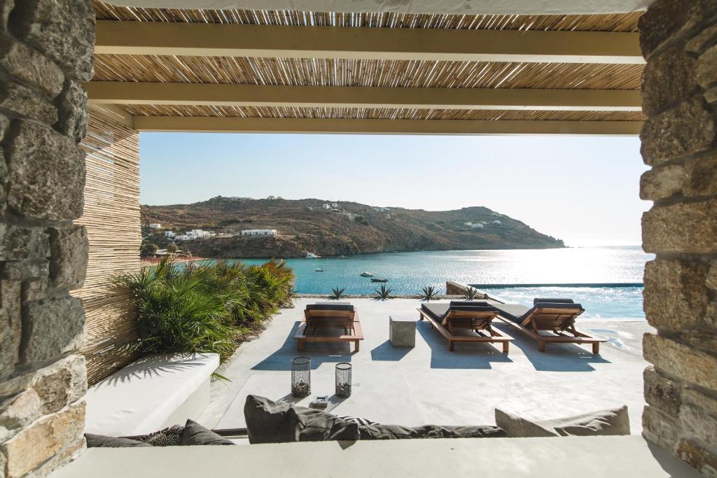 a patio with tables and chairs on the beach at Nimbus My Aktis in Super Paradise Beach
