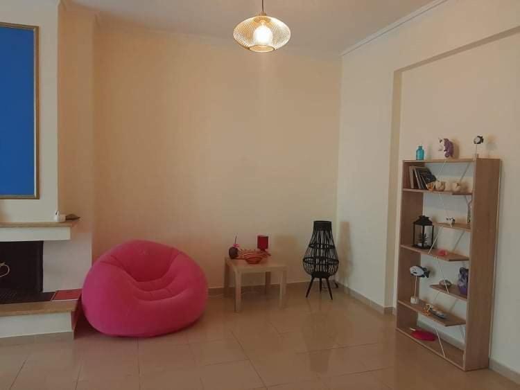 una sala de estar con una silla rosa en el centro de una habitación en Lovely house en Athens