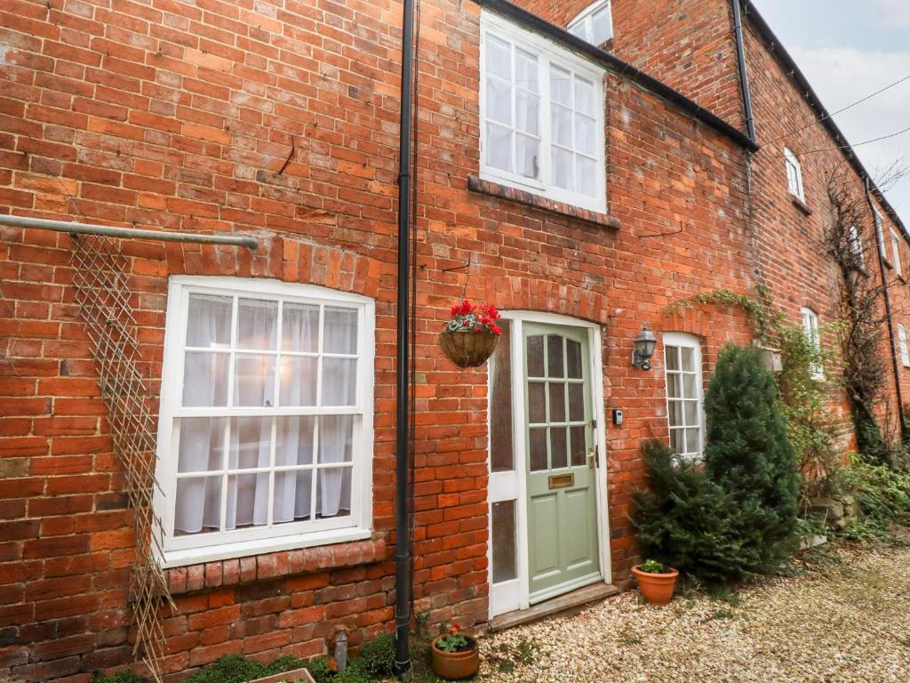 a brick house with a green door and windows at 5A Waterfall Way in Market Harborough