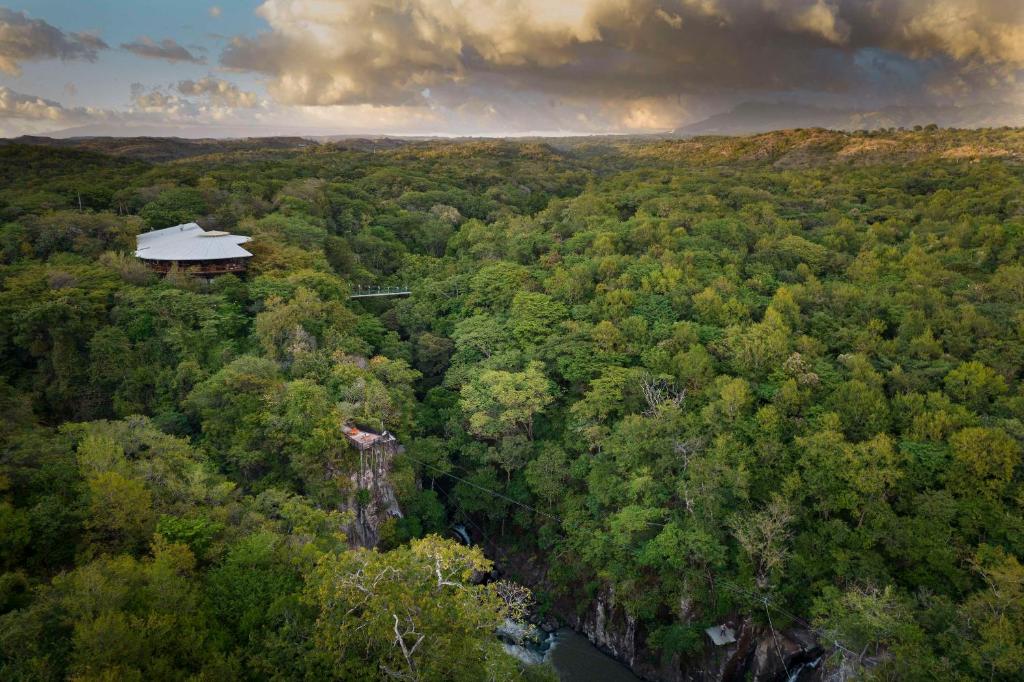 une vue aérienne sur une forêt avec une maison dans l'établissement Rio Perdido Hotel & Thermal River, à Fortuna