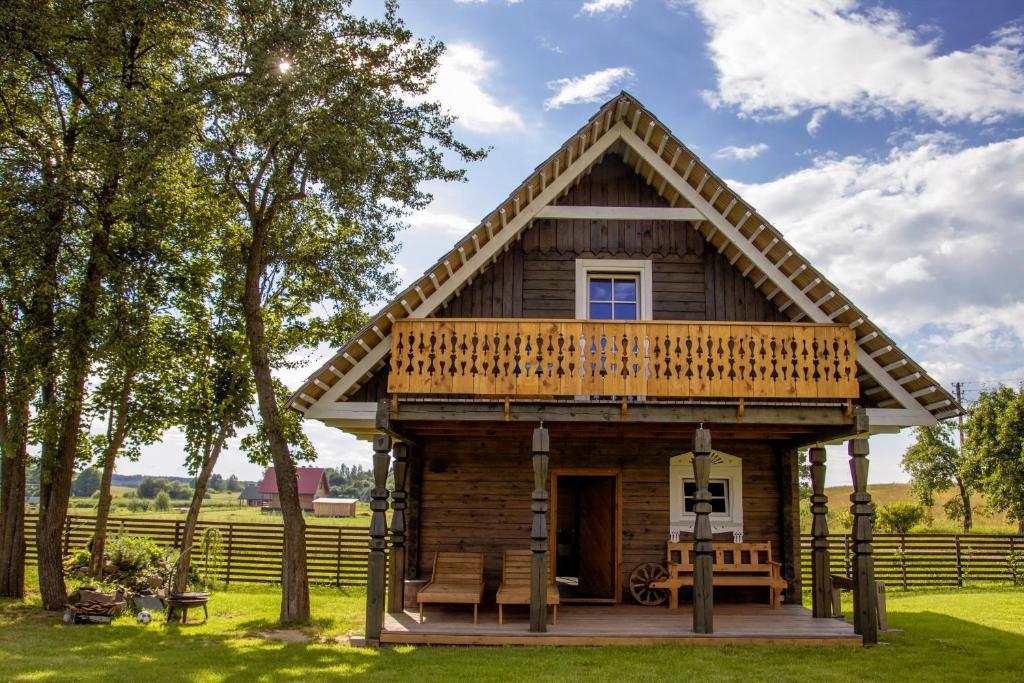 a small wooden house with a porch and a deck at Barškulių Sodyba in Ricieliai