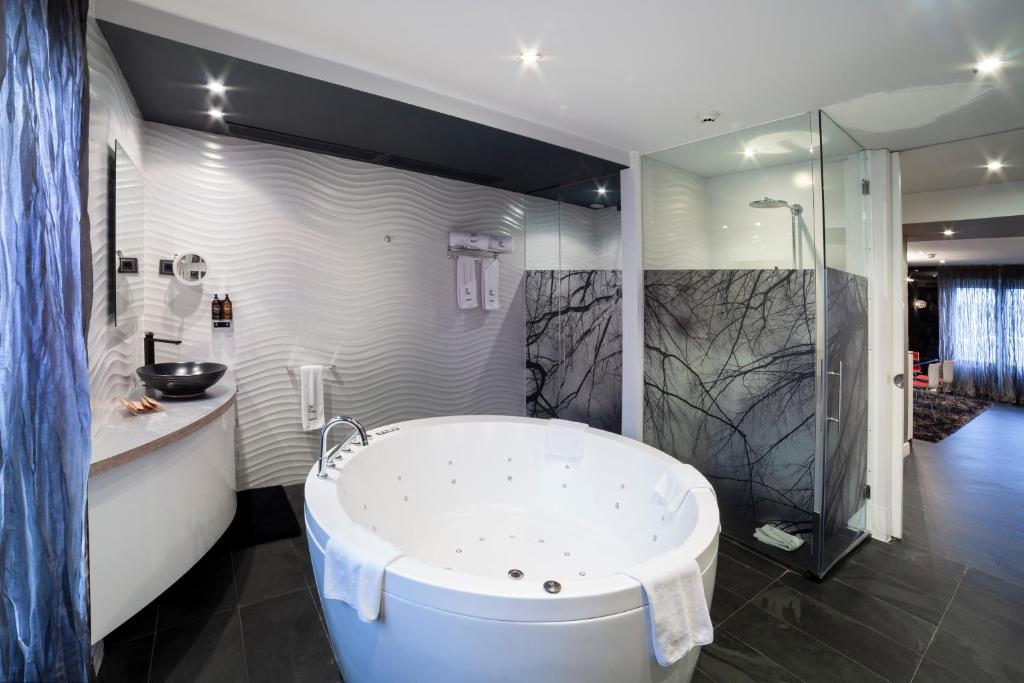 Un baño grande con bañera y ducha. en Petit Palace Savoy Alfonso XII, en Madrid