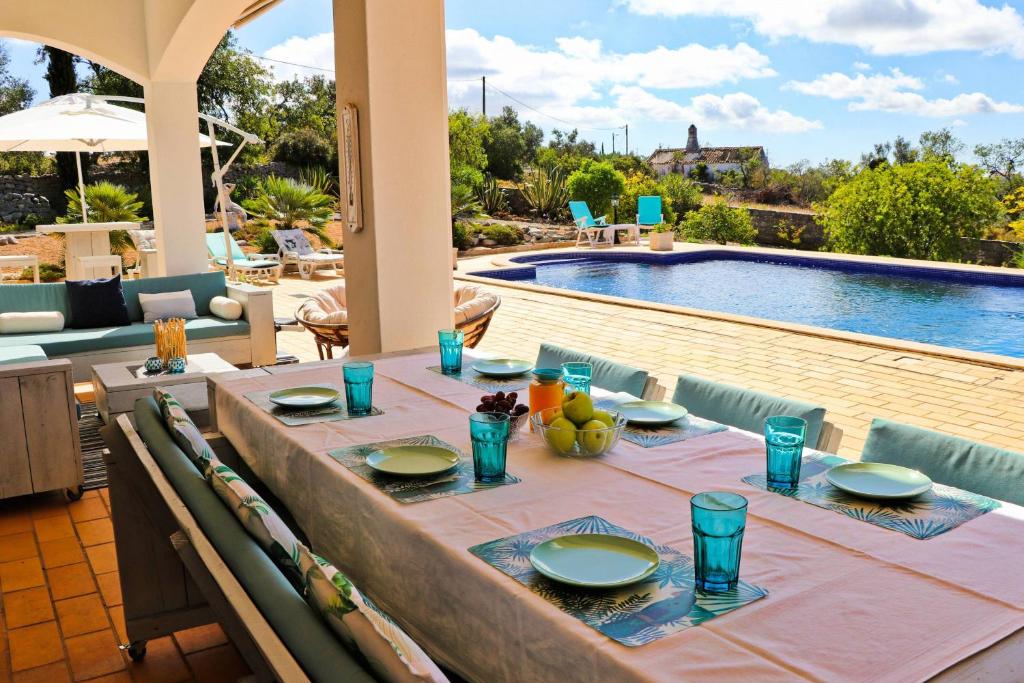 a table with plates of food on it next to a swimming pool at Villa Santa Barbara by Portucasa in Bordeira