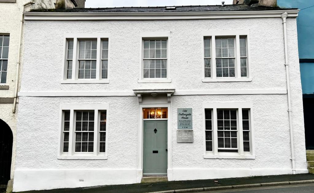 een wit huis met een groene deur in een straat bij Old Daltongate House in Ulverston