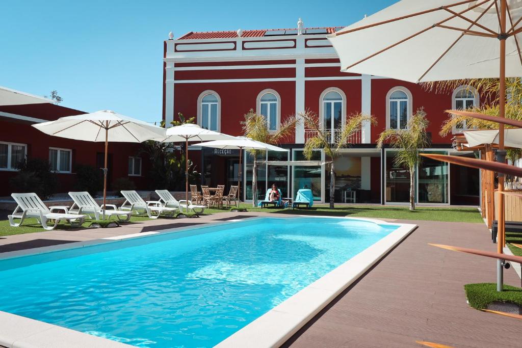 a swimming pool in front of a building with umbrellas at Salmanha Residence in Figueira da Foz